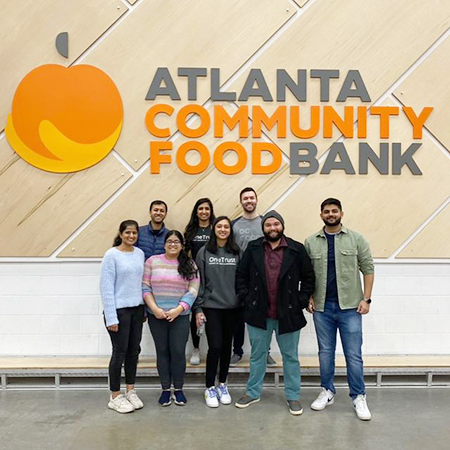 OneTrust team members pose in front of the Atlanta Community Food Bank logo